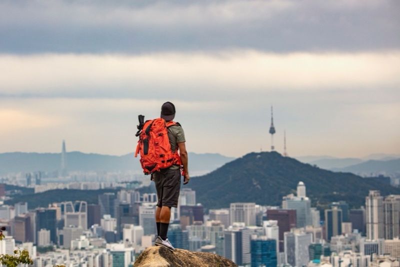 Wanderer mit Rucksack vor der Stadtsilhouette