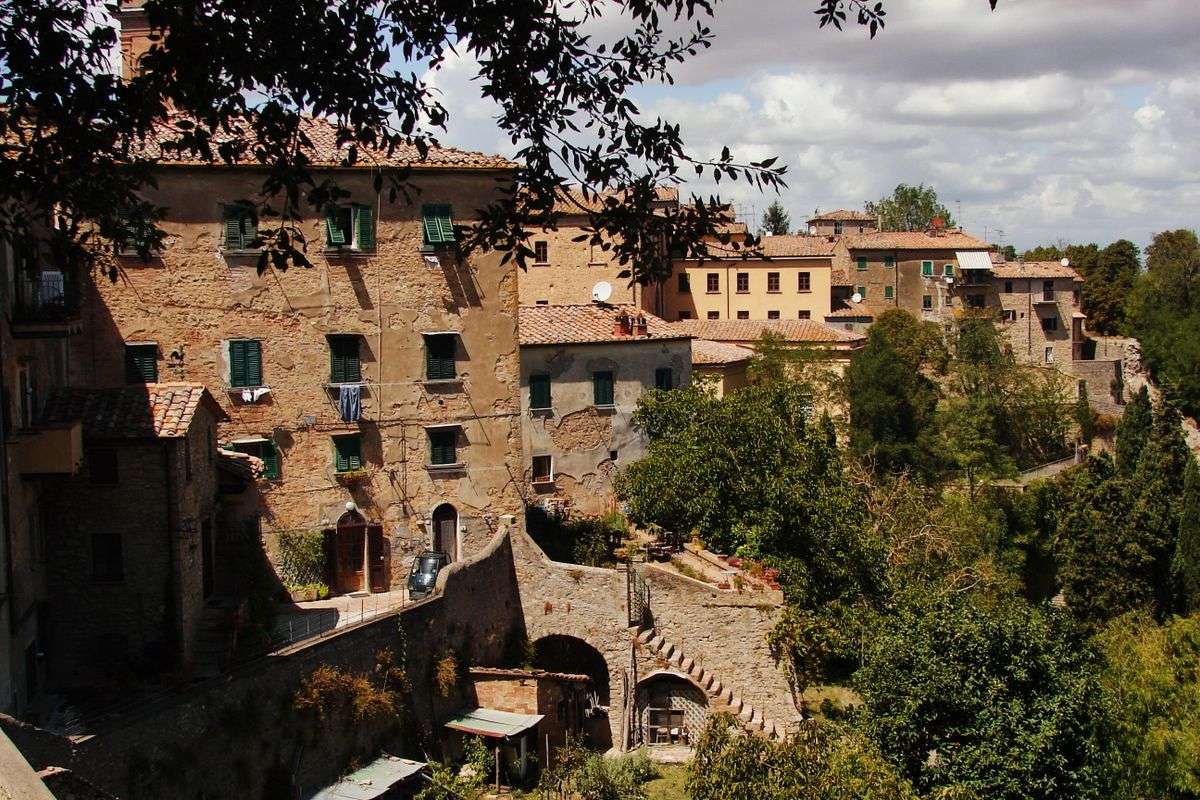 Rustikale Steinhäuser am Hang mit Bäumen und Treppen in Volterra