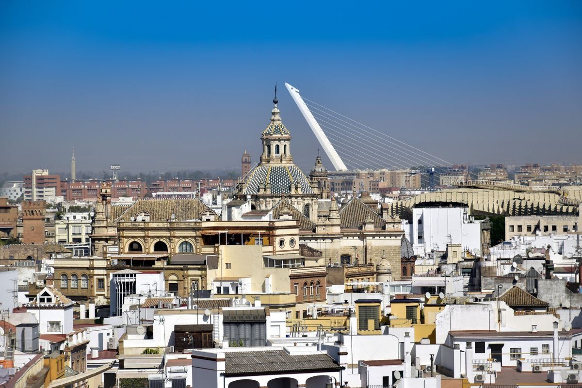 Blick über die Dächer von Sevilla mit Kuppel und Puente del Alamillo im Hintergrund
