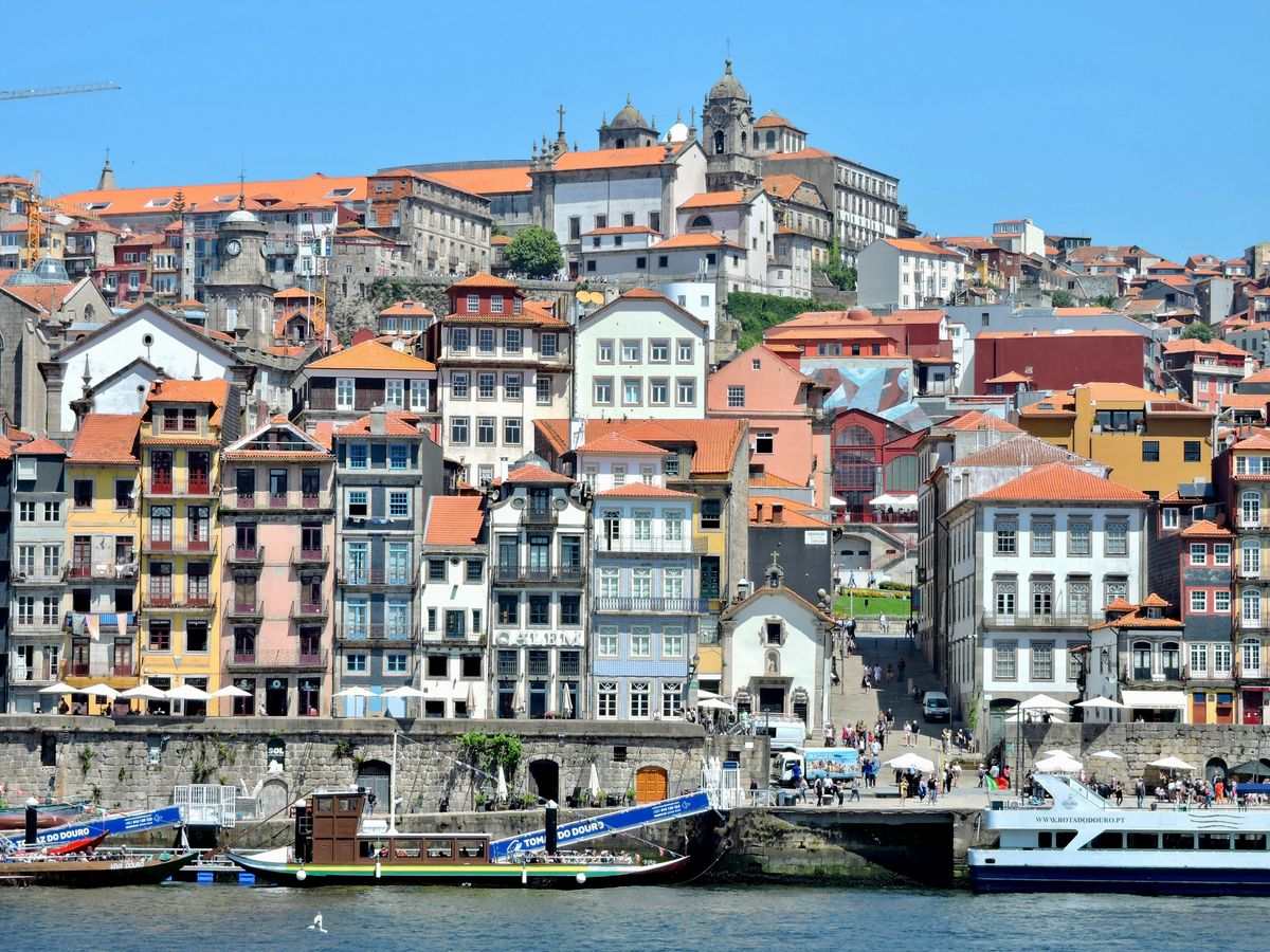 Bunte Häuserzeile im Viertel Ribeira am Douro mit dicht bebautem Hang im Hintergrund