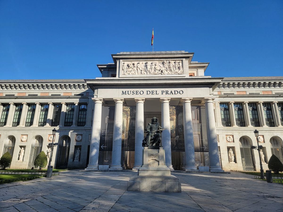 Front des Museo del Prado mit Säulenfassade und Statue unter blauem Himmel