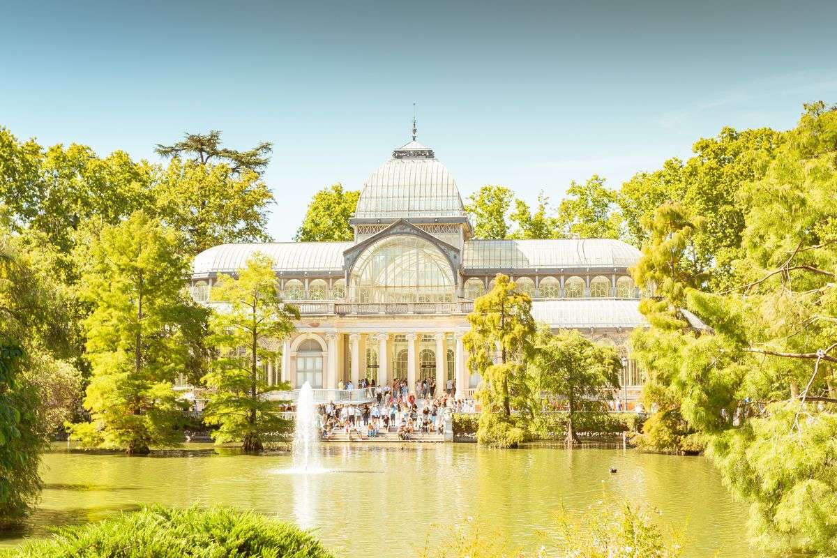 Glaspalast im Retiro-Park am Teich mit Springbrunnen und Bäumen