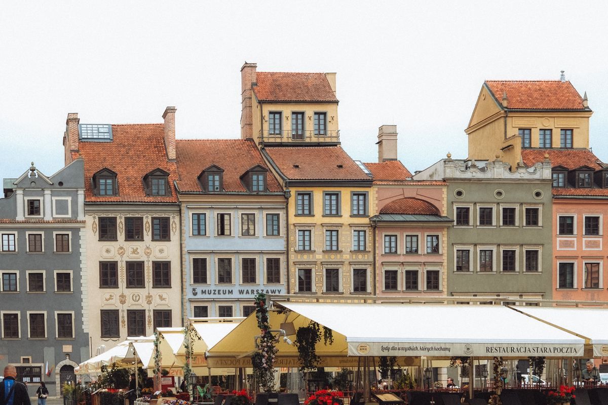Reihe farbiger Altstadthäuser mit roten Dächern und Cafés am Platz