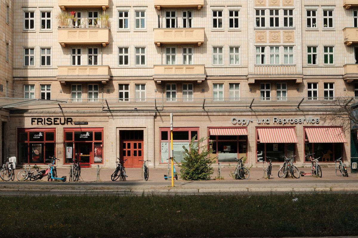 Straßenzug mit Fahrrädern vor Friseur und kleinen Geschäften in einem Berliner Wohnhaus
